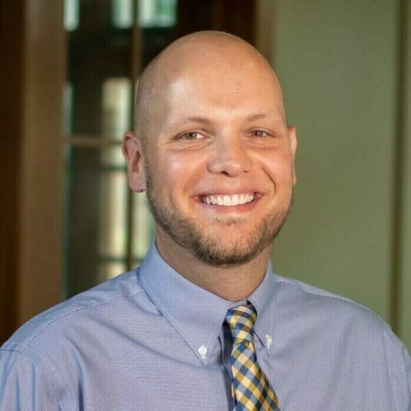 Headshot of Adam Gustine in a tie