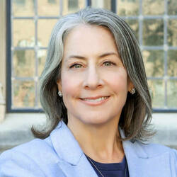 Woman with shoulder length gray hair in blue suit