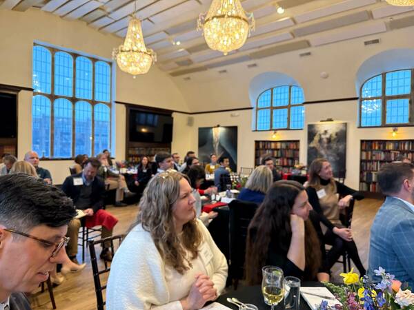 A group of diverse attendees listens intently at a dinner event.